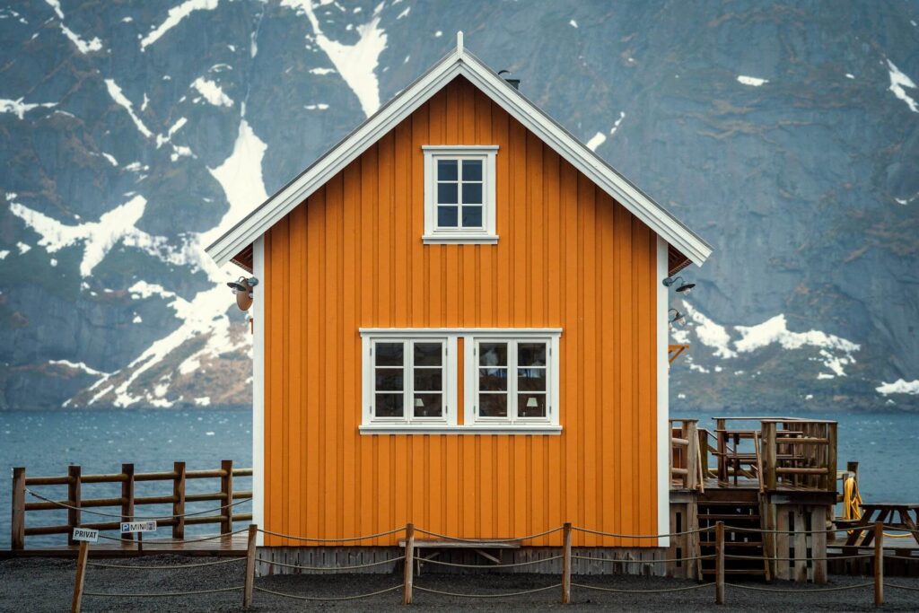 Orange fasadfärg på ett hus med berg i bakgrunden.