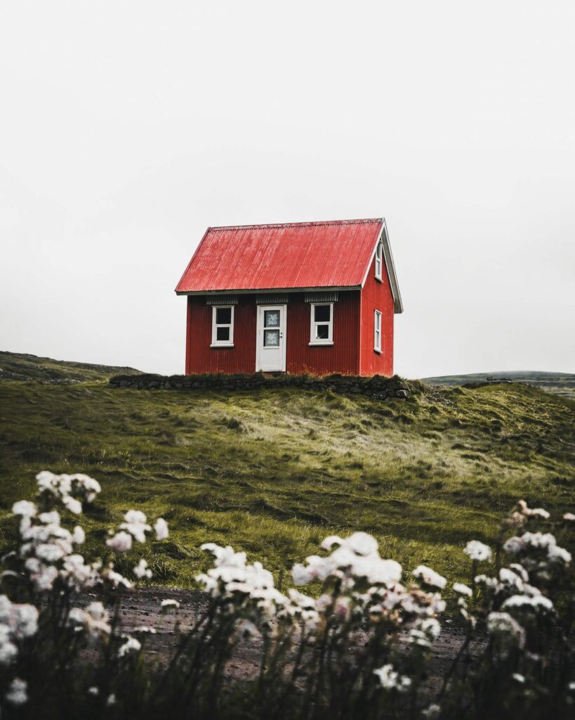 Rött hus på en grön kulle efter genomförd fasadmålning.