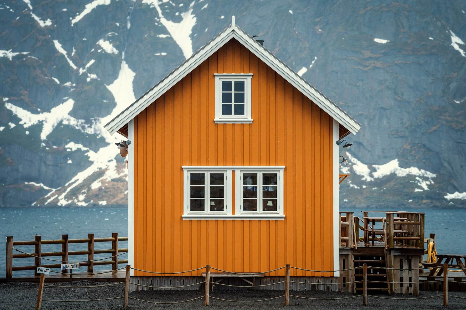 Orange fasadfärg på ett hus med berg i bakgrunden.